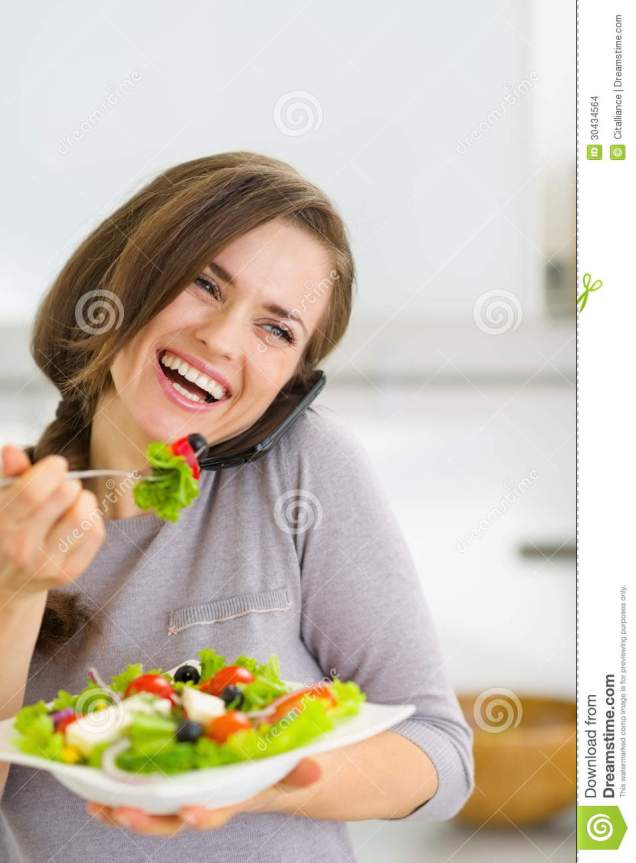 smiling-woman-eating-salad-talking-mobile-phone-young-kitchen-30434564.jpg